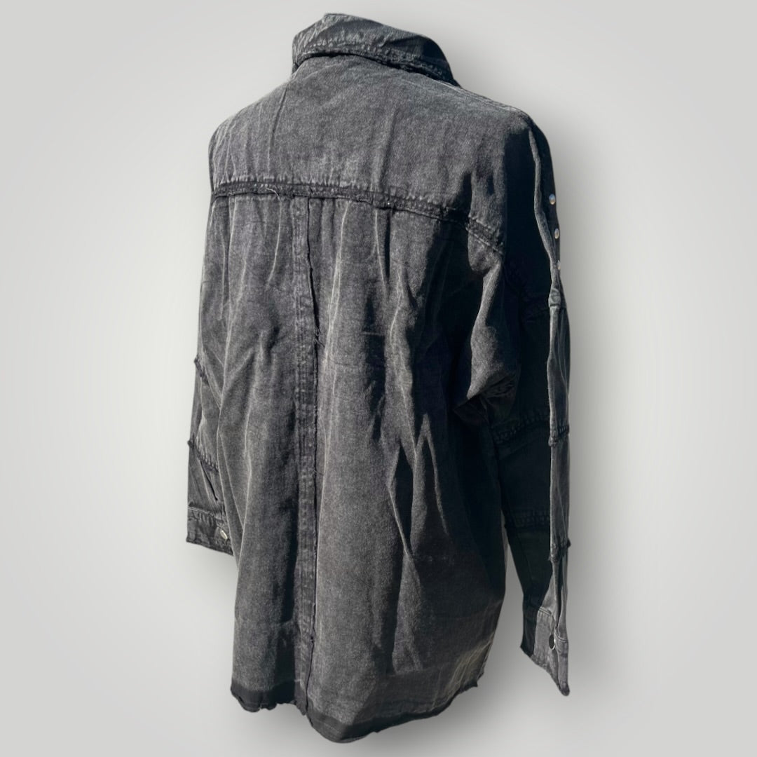 A washed black denim jacket shown from the back, featuring a collar, long sleeves, and a buttoned front, photographed against a neutral light gray background.