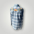 A blue and white plaid long-sleeve shirt shown from the back, featuring colorful floral embroidery across the upper back and shoulders.