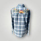 A blue and white plaid long-sleeve button-up shirt shown from the back, featuring a colorful embroidered floral design across the upper back.