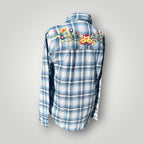 A blue and white plaid long-sleeve button-up shirt shown from the back, featuring colorful floral embroidery across the upper back.
