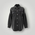 A black washed denim button-up shirt jacket with silver studs on the shoulders and chest, displayed on a black mannequin torso against a light gray background.