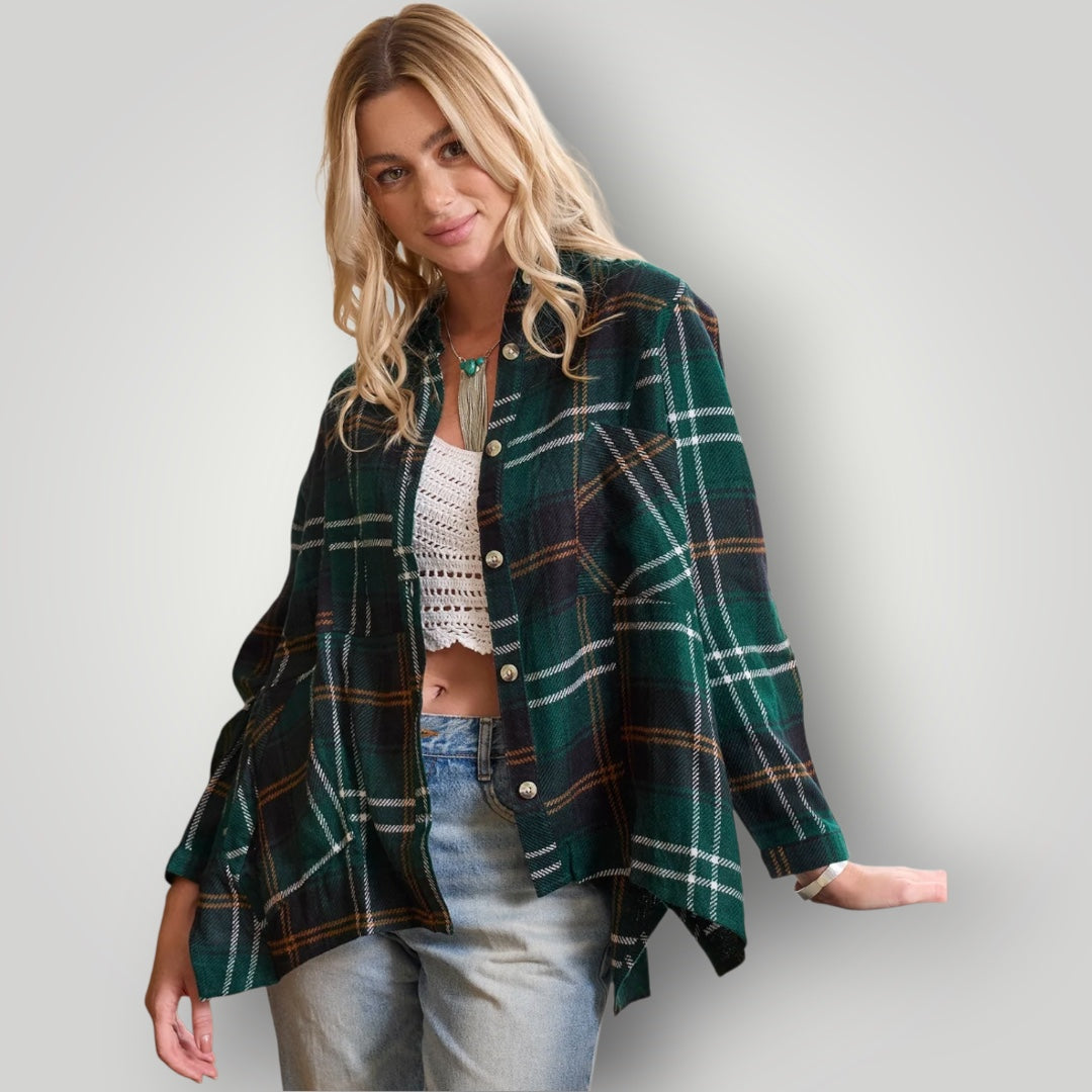 A woman modeling a green plaid button-up shirt with white and brown stripes, worn open over a white crochet top and light blue jeans, against a light gray studio background.